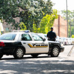 Alabama city police officer car on street, with sign, people walking on sidewalk, blocked road block or roadblock