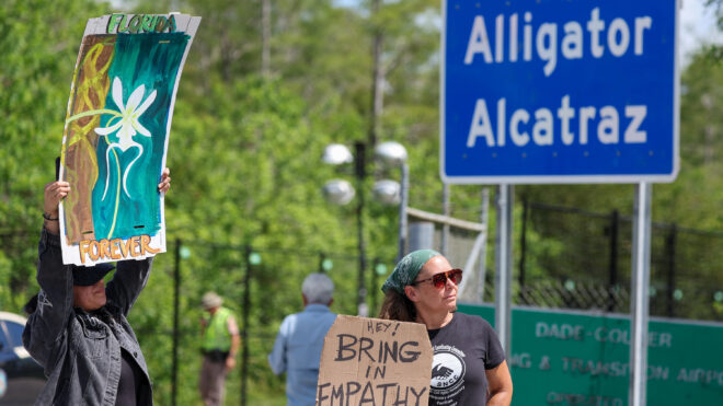 Ashlie Soto of Lehigh Acres and Jill Cicero of Naples, Florida, hold up signs outside of Alligator Alcatraz on July 12, 2025, in Ochopee. (Luis Santana/Tampa Bay Times/TNS)