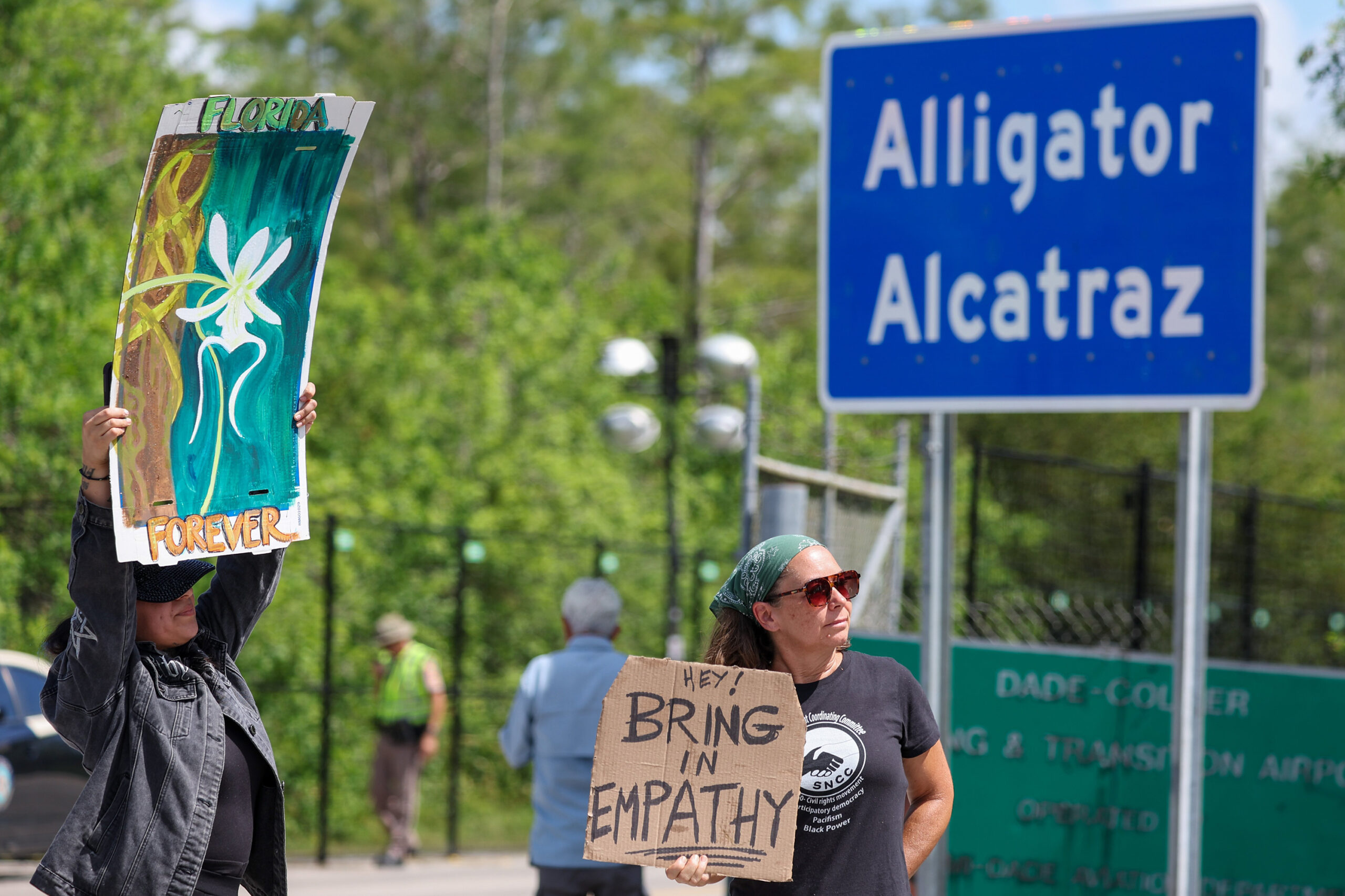 Ashlie Soto of Lehigh Acres and Jill Cicero of Naples, Florida, hold up signs outside of Alligator Alcatraz on July 12, 2025, in Ochopee. (Luis Santana/Tampa Bay Times/TNS)