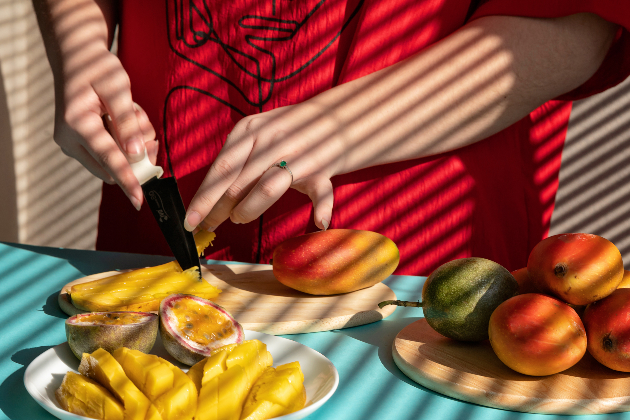 Female hands cutting mango and passion fruit, fruit breakfast