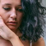 Young woman touching face, may be feeling or sad or afraid