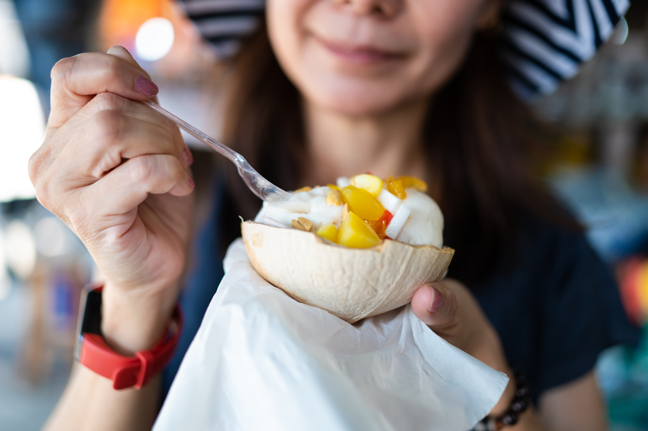 Close-up of an Asian female traveler savoring ice cream at Bangkok market