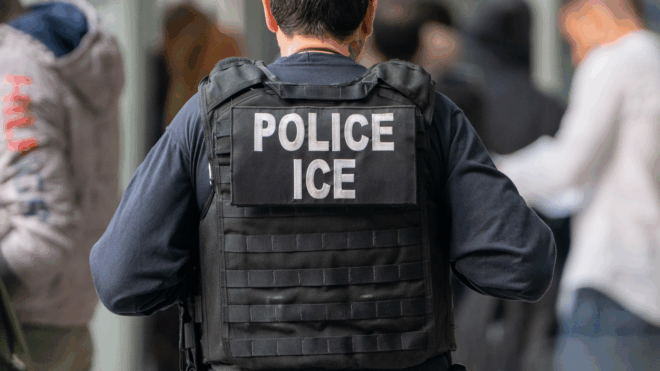 An ICE agent monitors hundreds of asylum seekers being processed upon entering the Jacob K. Javits Federal Building on June 6, 2023 in New York City.