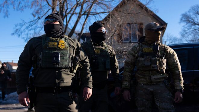 ICE agents walk down a block near 31st St. and Portland Ave. to confront observers