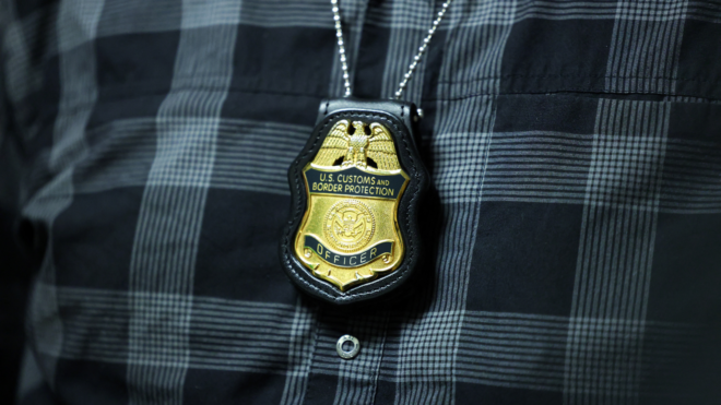 A federal agent's badge hangs from his neck